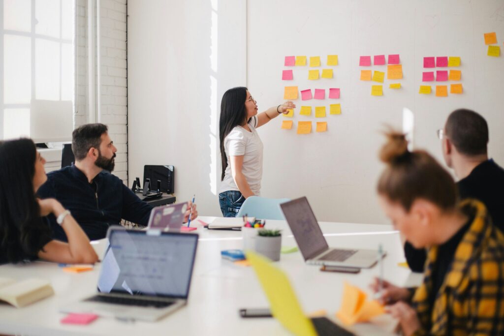 Group of people in an office working on a whiteboard with sticky notes